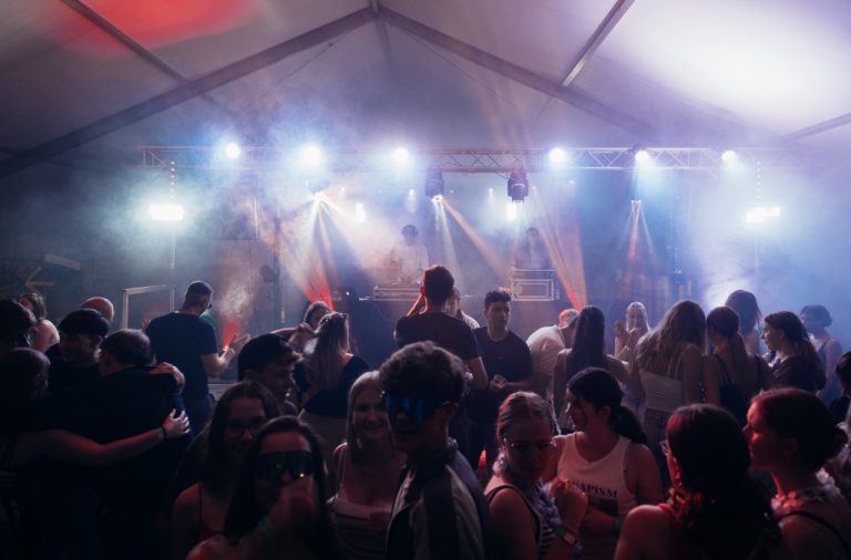 Kirmes Menschen tanzen in einem festlichen Zelt unter buntem Licht.